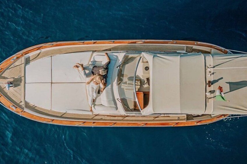 A boat with a person lying on the deck, surrounded by a clear blue sea. 4