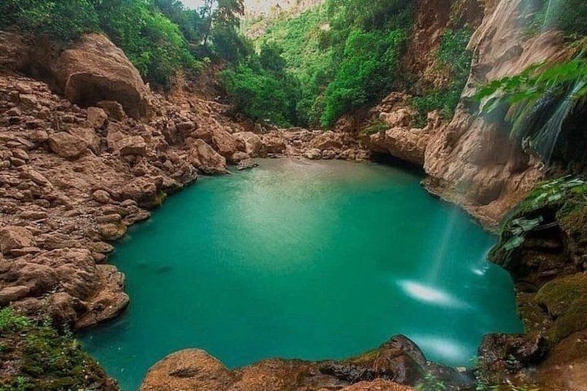 A turquoise lake surrounded by rocky cliffs and lush greenery. 4