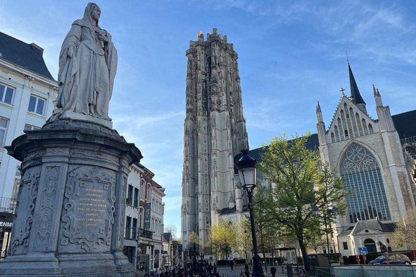A statue, a tall church, and a cathedral in a city square. 2