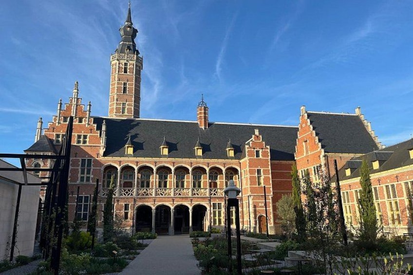 A historic building with a prominent tower, arched windows, and a central courtyard. 4