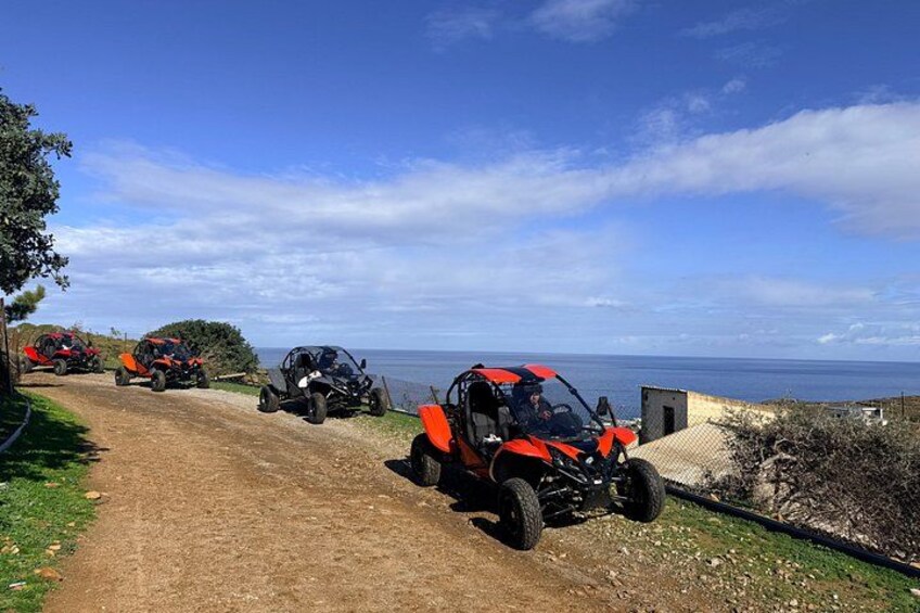 Veicoli fuoristrada parcheggiati su un sentiero sterrato con vista sulla costa. 1