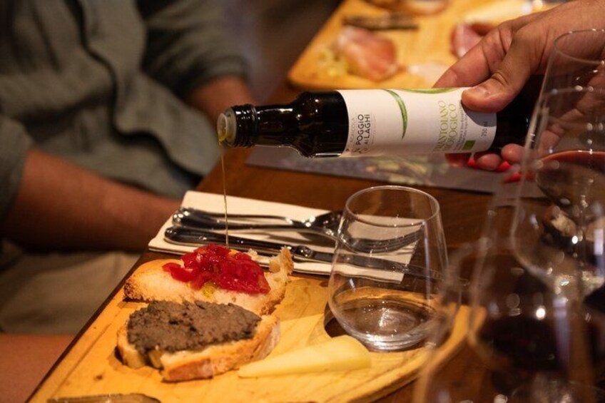 A person pouring a dark liquid from a bottle onto a slice of bread with red topping. 3