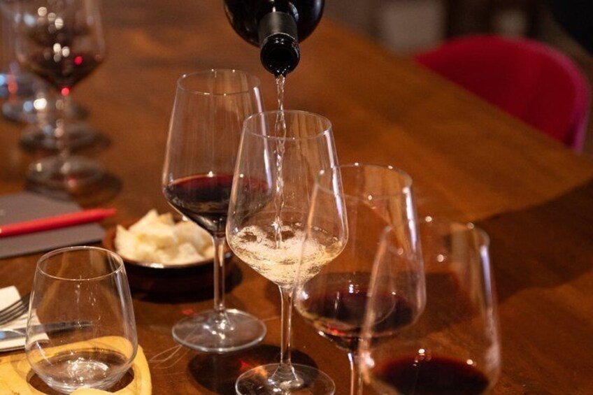 Wine glasses on a table with a bottle being poured into one of them. 2