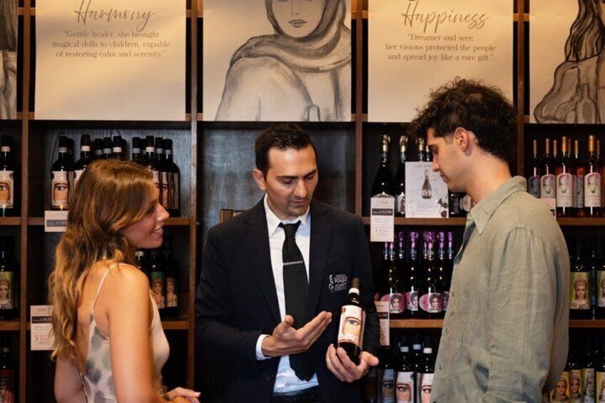 A person holding a bottle, standing in front of shelves with bottles. 1