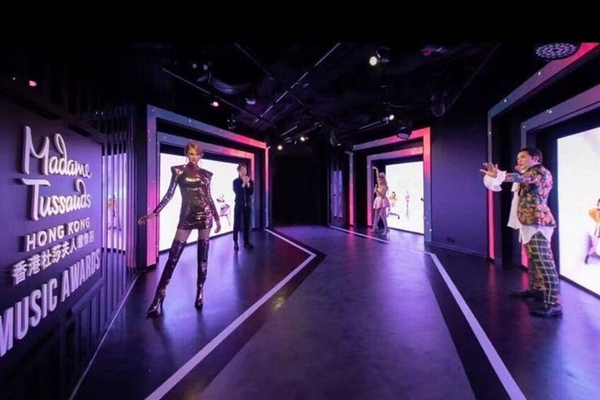 A stage with performers, a large screen, and event signage. 3