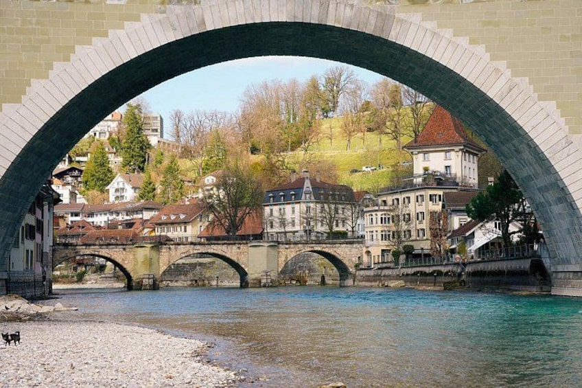 A stone bridge over a river with buildings and trees in the background. 2