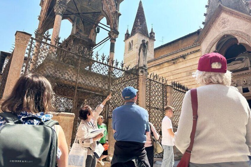 Tourists at a historical gate with intricate metalwork and a tower in the background. 4
