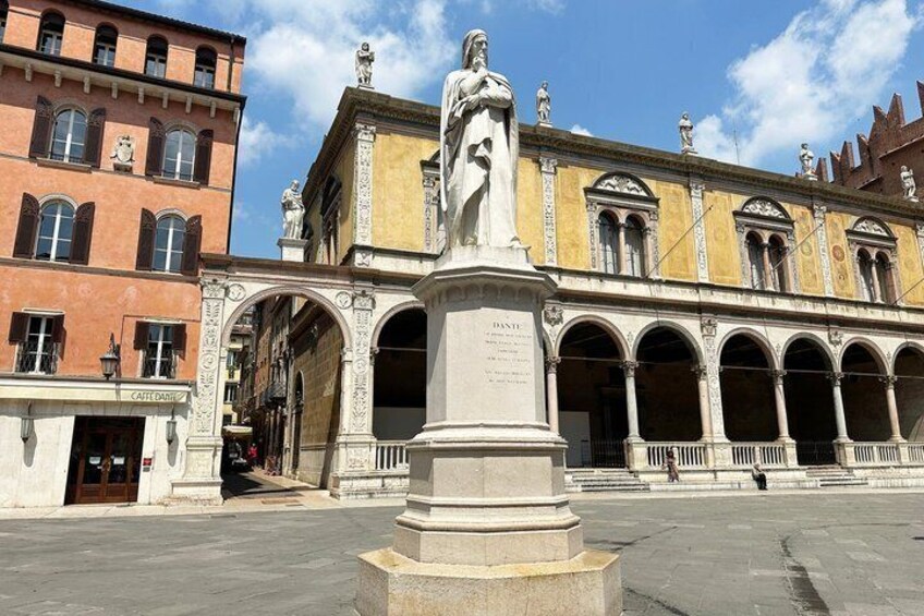 A historic building with arches and a statue in the foreground. 2