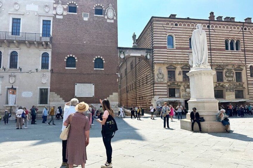 A public square with a statue, historic buildings, and people walking. 3