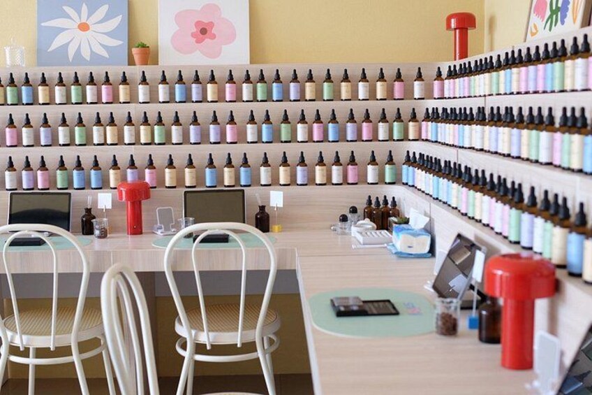 A salon with rows of hair dye bottles, a laptop, and a red container on the counter. 4