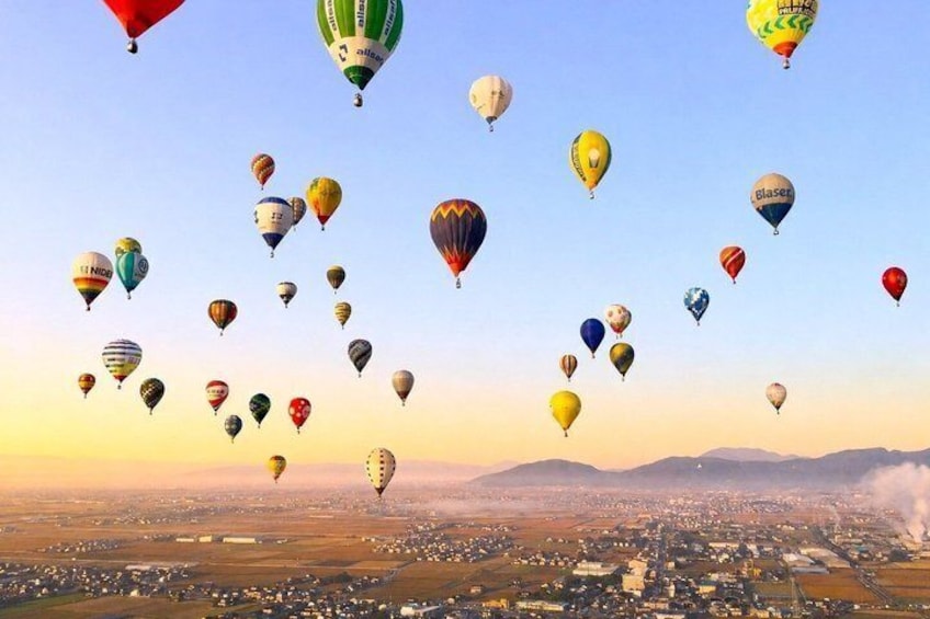 A cityscape with numerous hot air balloons in the sky. 1