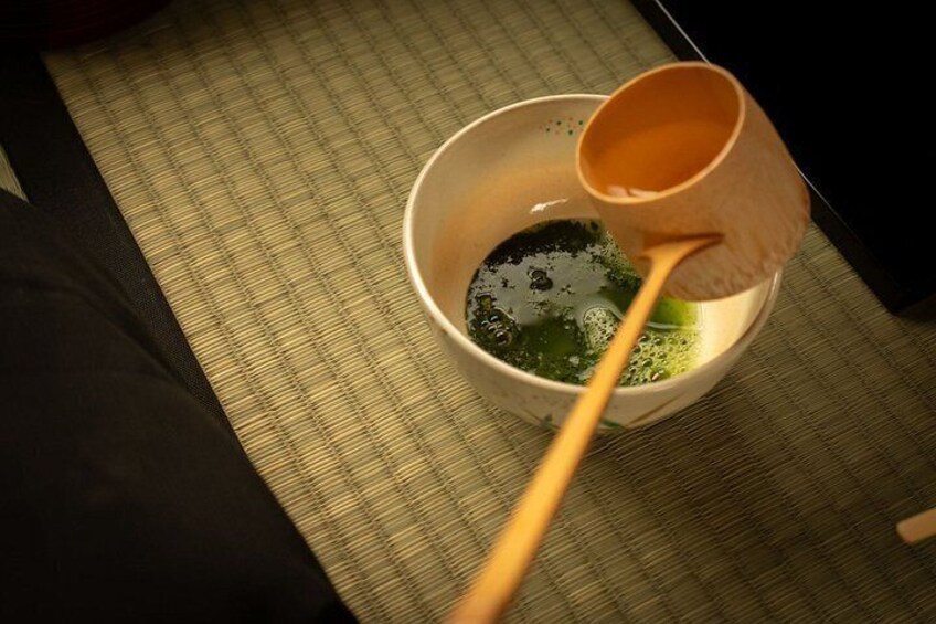 A wooden cup with a spoon, containing a dark liquid, on a textured surface. 5