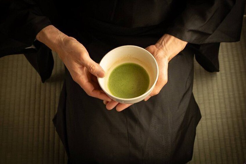 A person holding a white cup with green liquid. 4