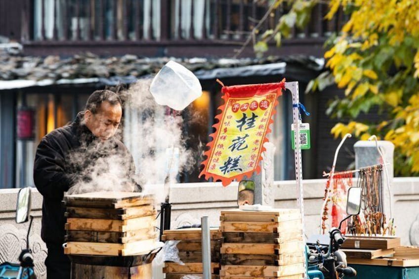 Un vendedor ambulante cocina comida, con humo saliendo del fogón y cajas de madera apiladas cerca. 5