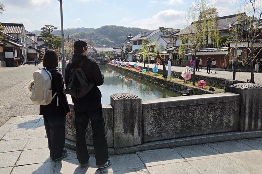 A traditional Japanese street with a canal, stone lanterns, and traditional buildings. 1