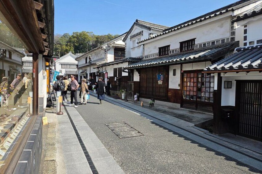 A traditional Japanese street with pedestrians, wooden buildings, and a clear sky. 5