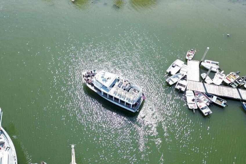 A riverboat docked at a pier with several smaller boats moored nearby. 2