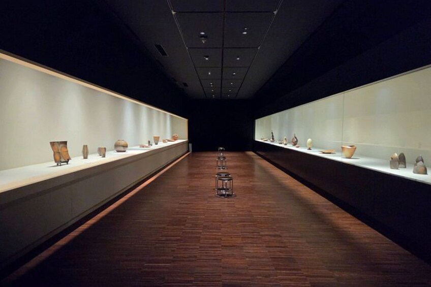 En museumsgang med glasvitrines fyldt med keramik. 1