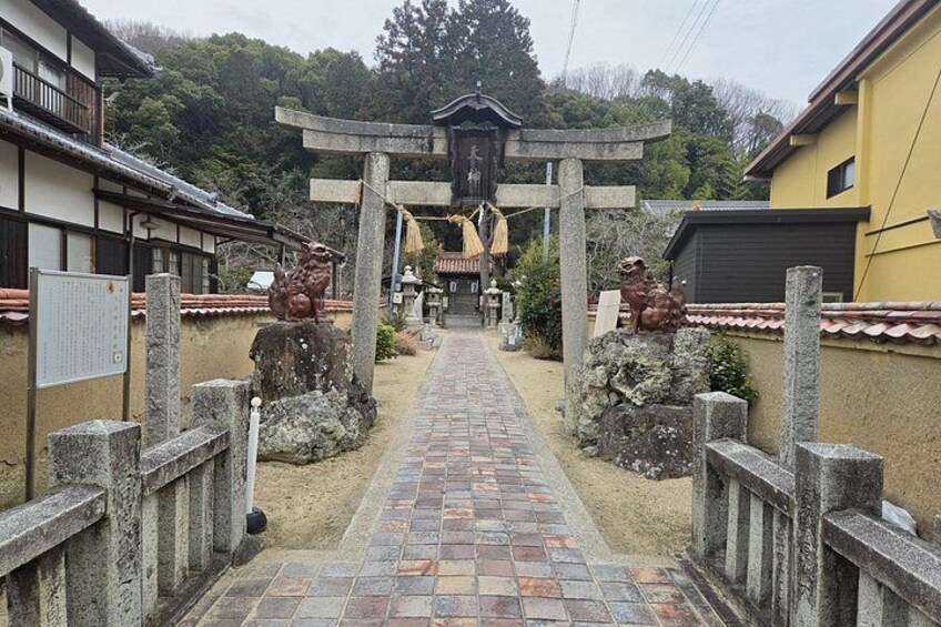 En traditionel japansk sti, der fører til en torii-port, med stenhus og en træbygning på hver side. 5