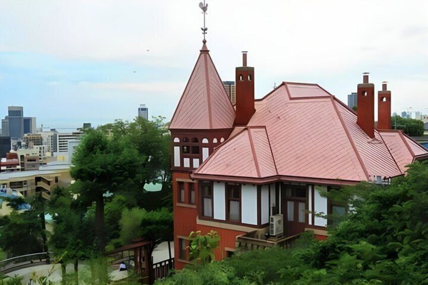 A Victorian-style house with a red roof and multiple chimneys, surrounded by lush greenery. 4