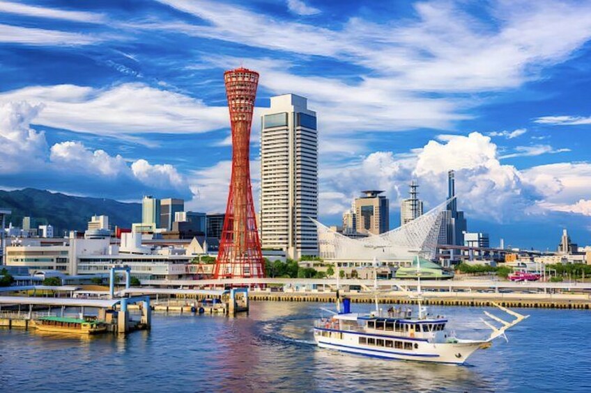 A cityscape with a prominent red tower, a white boat on the water, and modern buildings. 1