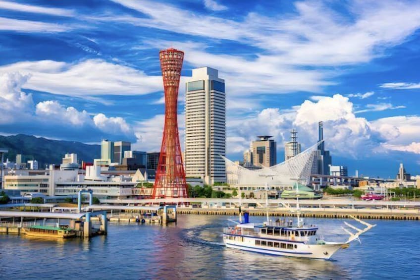 A cityscape with a distinctive red tower, a white boat on the water, and modern buildings. 1
