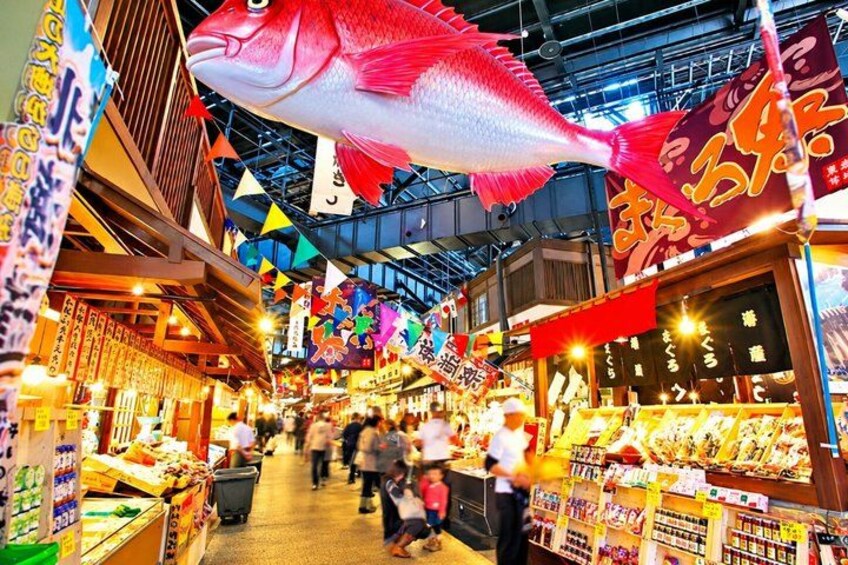Een levendige overdekte markt met verschillende kraampjes en een grote visdecoratie. 4