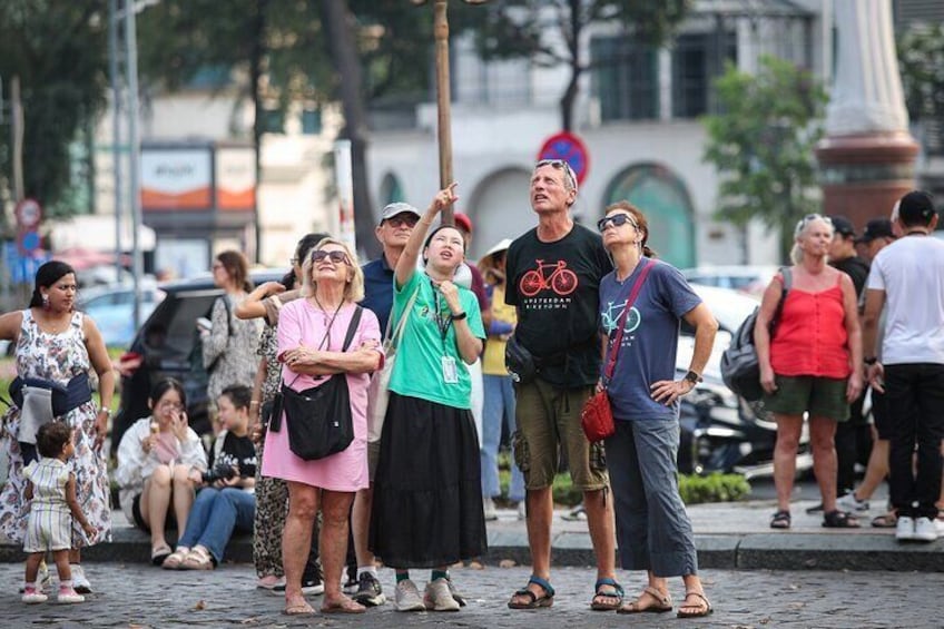 Un groupe de personnes se tient sur une rue pavée, et certaines regardent un grand poteau. 5