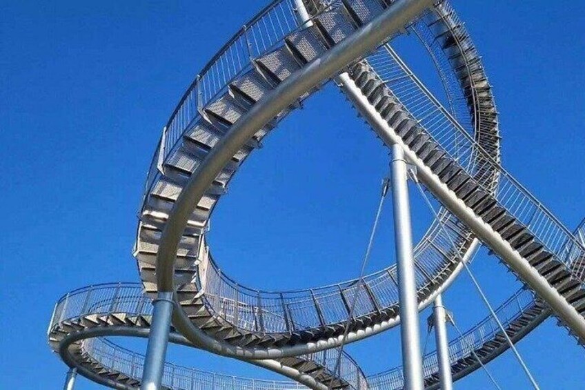A large, spiral roller coaster with a clear blue sky in the background. 3