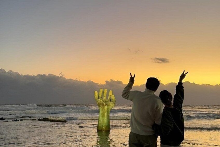 Two people standing on a beach with a sunset in the background. 2