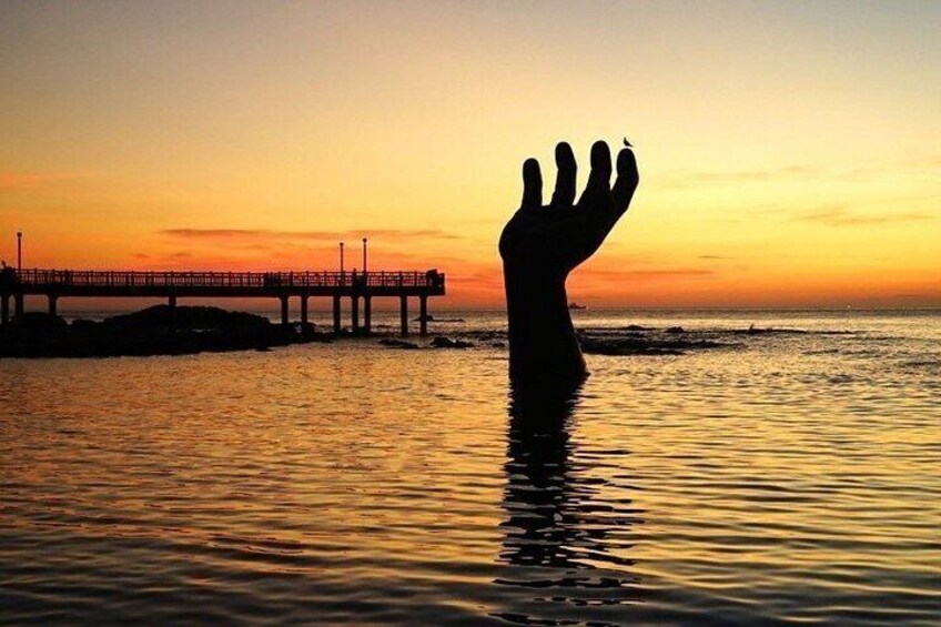 A sunset over a body of water with a pier and a hand silhouette. 5