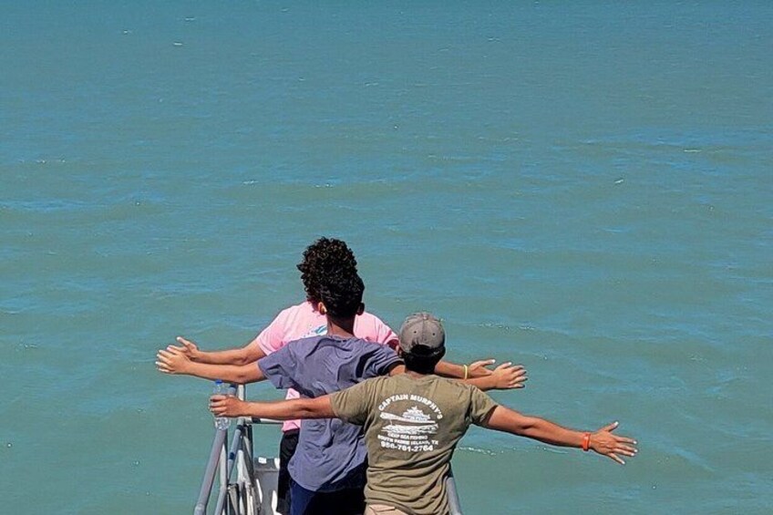 Drie mensen staan op een steiger met hun armen wijd over het water. 5