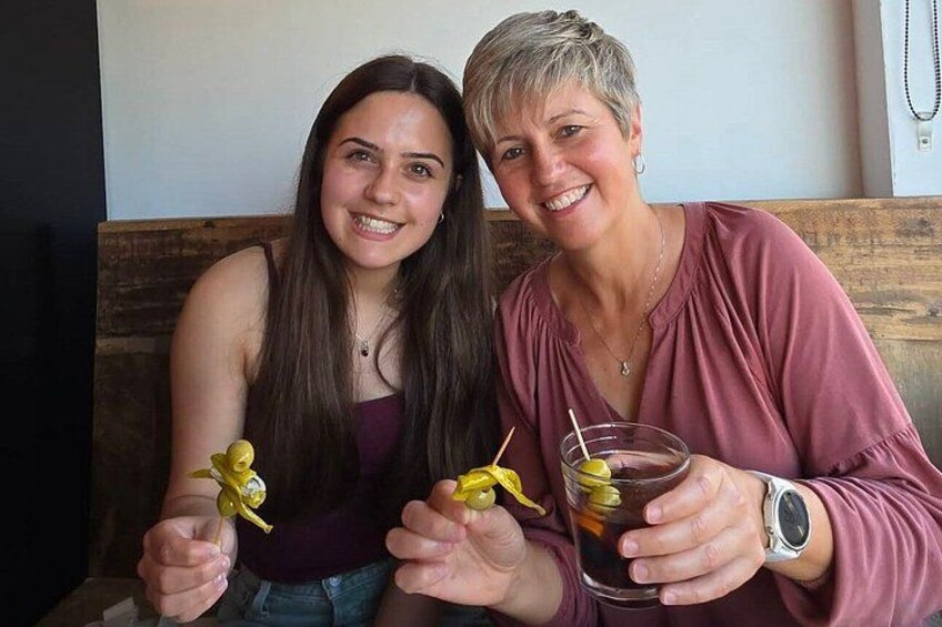 Two people sitting at a table with drinks and a yellow object. 3