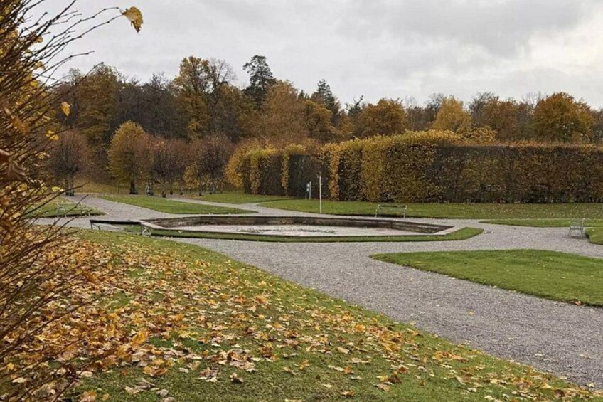 A landscaped garden with a circular water feature, pathways, and autumn foliage. 2