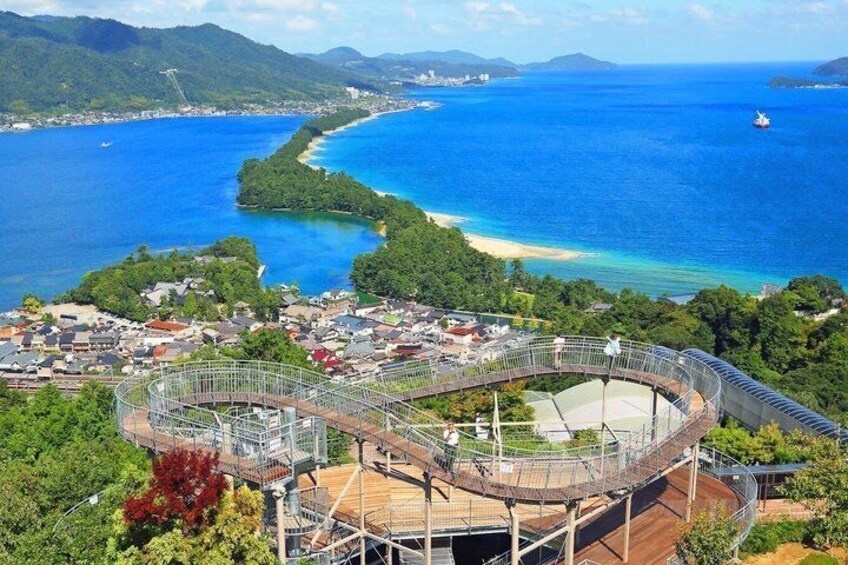 A coastal town with a large stadium, a winding road, and a clear view of the ocean. 1