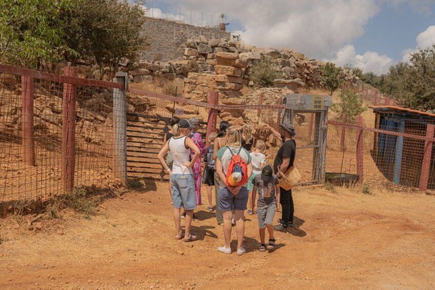 A group of people standing near a stone structure with a fence in the background. 2