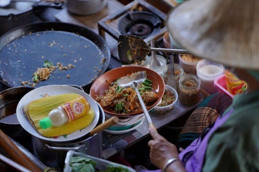 A person cooking with a pan, a bowl of food, and various condiments. 5