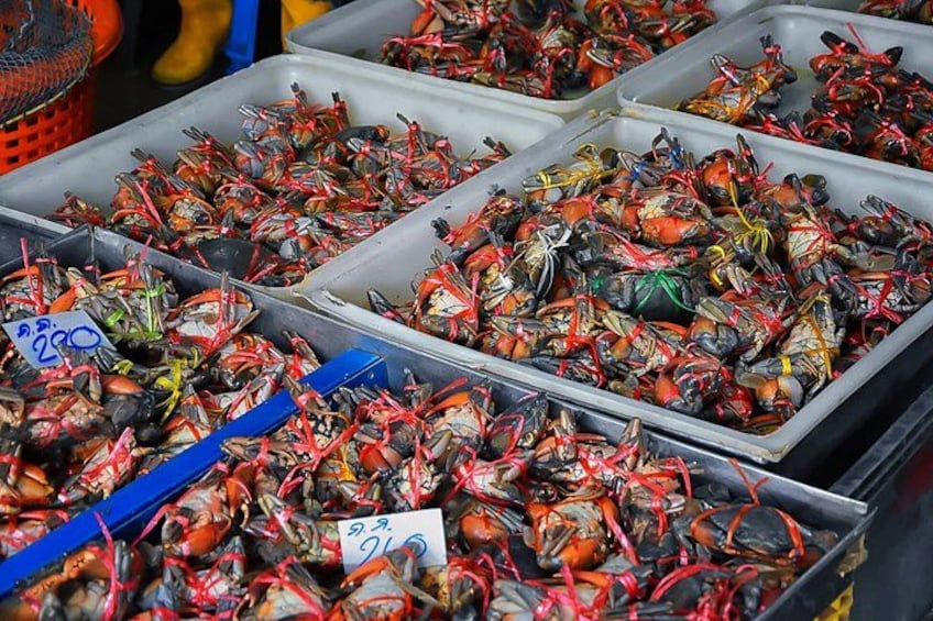 Seafood, specifically crabs, displayed in trays at a market. 4