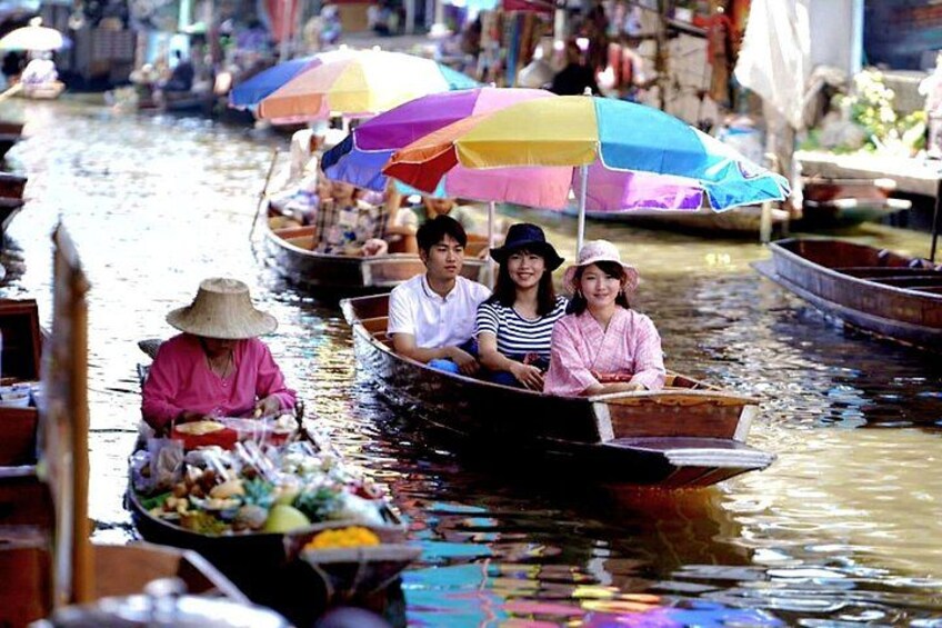 A narrow waterway with boats carrying passengers and goods, surrounded by market stalls and colorful umbrellas. 5
