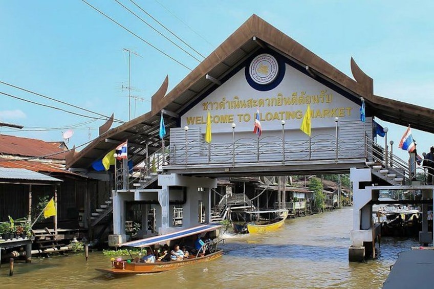 A floating market with boats, a building with a sign, and flags. 2