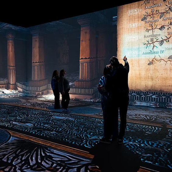 A grand hall with columns and a large illuminated map on the wall. 5