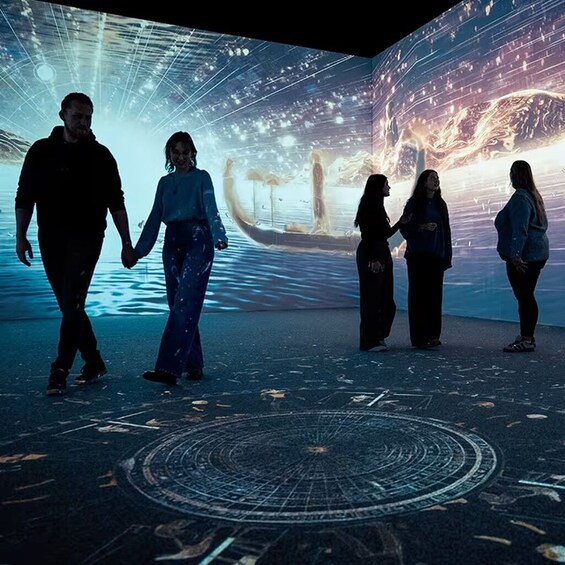 A group of people walking in a futuristic, illuminated room with a circular floor design. 2