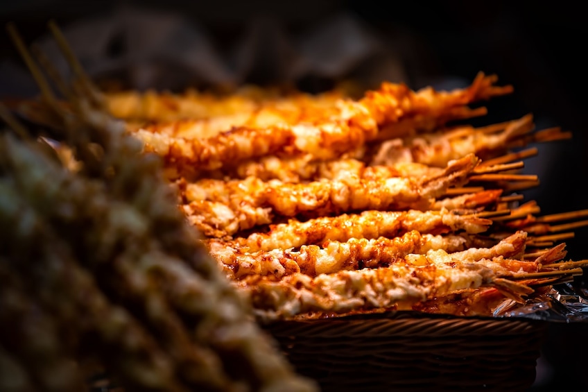 A basket of skewered food, likely a type of grilled dish, with a dark background. 5