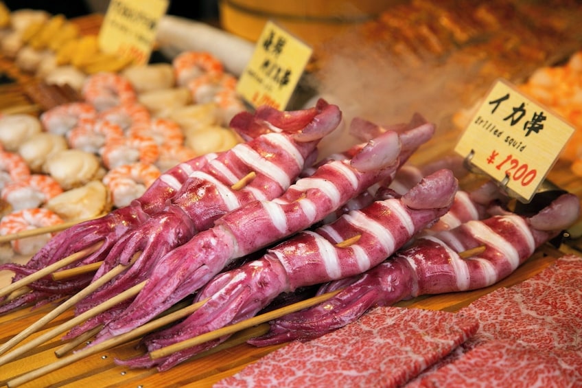 Skewers of grilled squid and other seafood at a market stall. 2