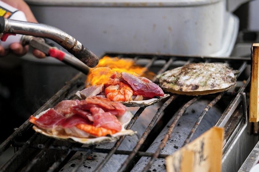 Seafood grilling on a grill with a person using a torch. 1
