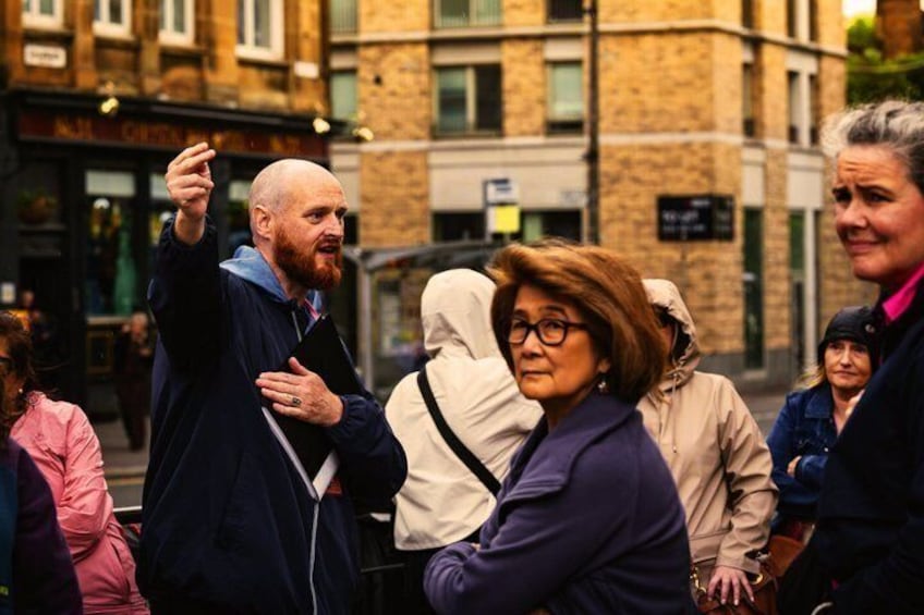 A group of people on a city street, some carrying bags and one person holding a phone. 4