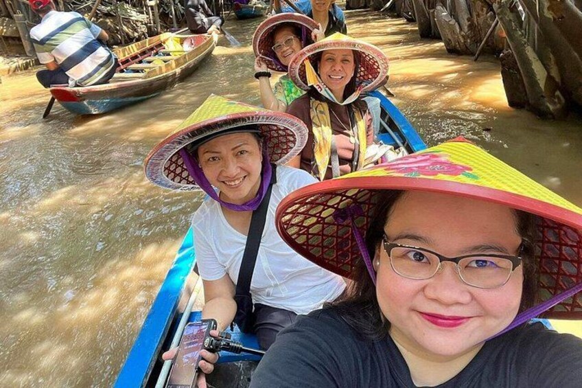 People in a boat with canopies, water, and boats in the background. 1