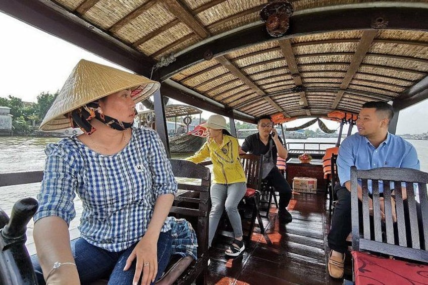 A boat with people wearing hats and casual clothing, a covered upper deck, and a river in the background. 4