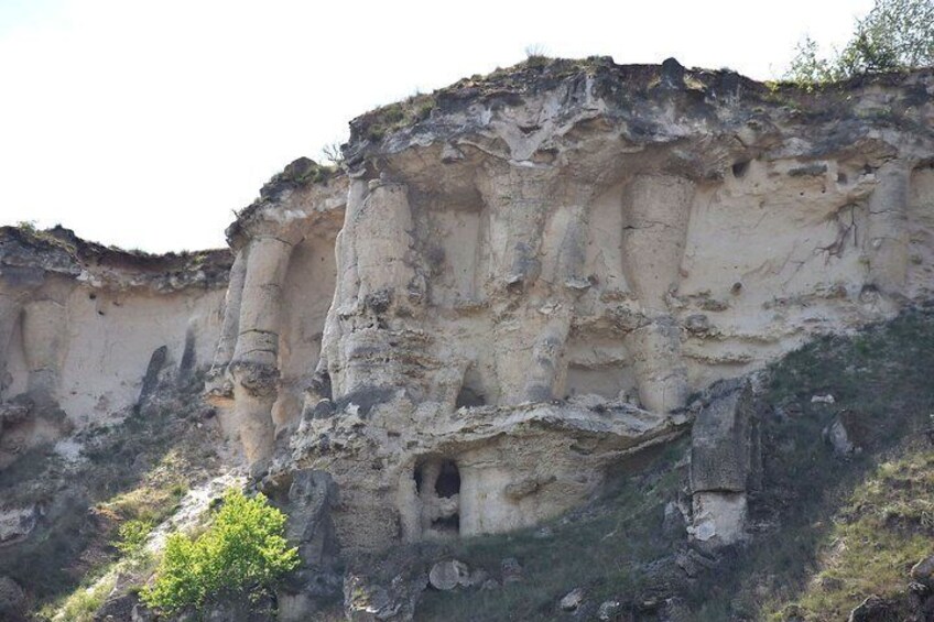 A rocky cliff with erosion patterns and a small cave entrance. 3