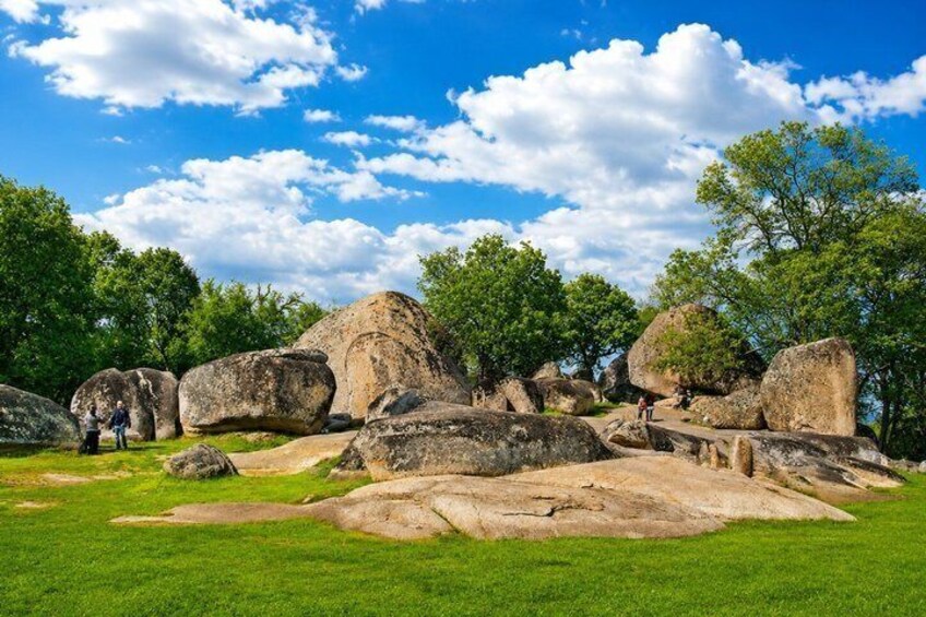 A landscape with large boulders and trees under a blue sky. 4